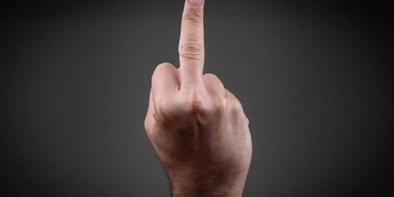 Eine Hand zeigt den Mittelfinger. Dies kann als Geste der Ablehnung oder als Zeichen der Rebellion gesehen werden, die eine Strafe nach sich ziehen kann.