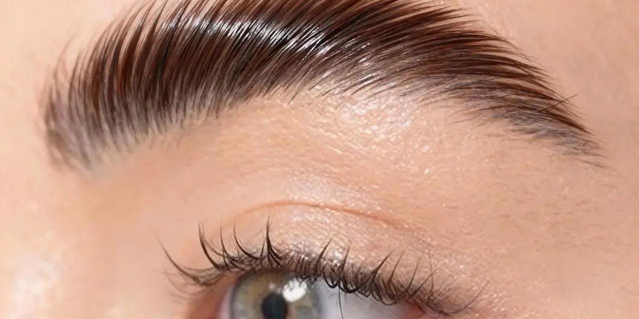 Un gros plan sur un œil et un sourcil parfaitement plaqué, montrant comment plaquer ses sourcils pour un look impeccable.