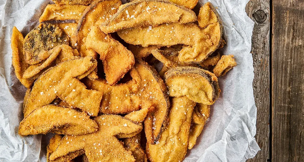 Un cesto pieno di croccanti funghi fritti, cosparsi di sale grosso, pronti per essere gustati.