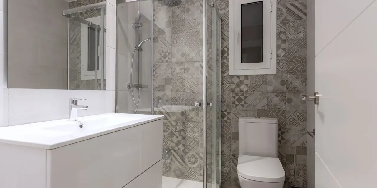 Salle de bain moderne avec douche vitrée, lavabo suspendu et carrelage graphique. Un projet pour agrandir salle de bain avec style.