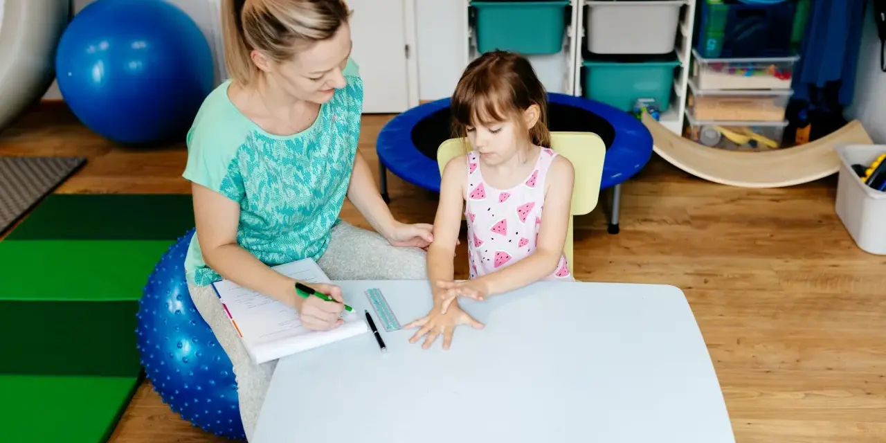Terapeuta ocenia reakcje dziecka podczas badania sensorycznego, sprawdzając jego wrażliwość dotykową i propriocepcję.