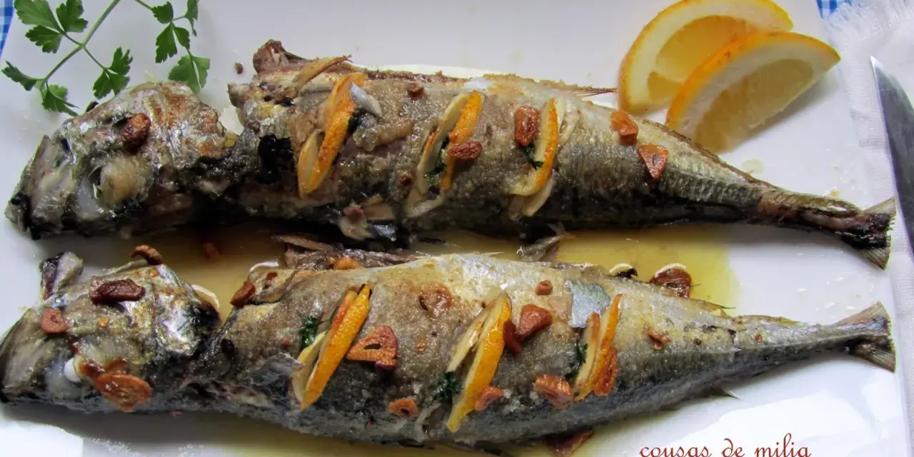 Dos jureles al horno, dorados y jugosos, con rodajas de limón y ajo. Un plato sencillo y delicioso.