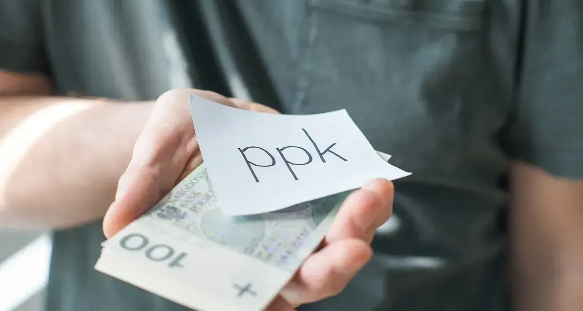 Dłoń trzyma banknoty i karteczkę z napisem "ppk". Jak sprawdzić swoje oszczędności?