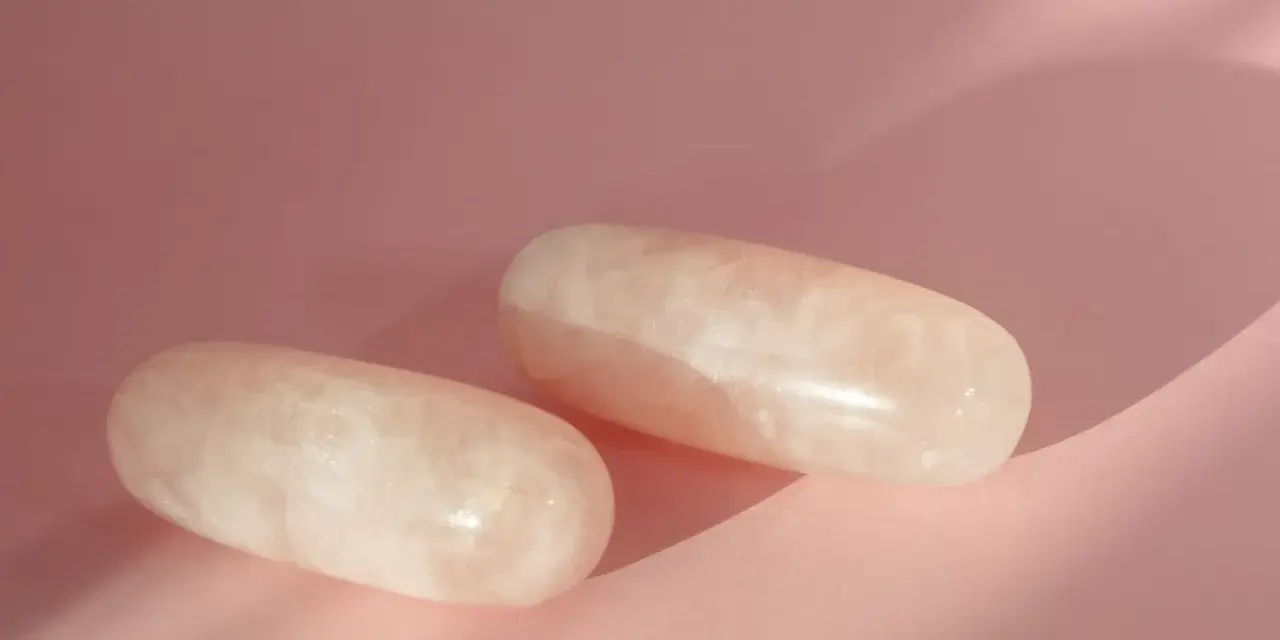 Dos piedras de cuarzo rosa pulidas, con vetas blancas, sobre un fondo rosa pálido. ¿Por qué el cuarzo rosa se pone blanco?