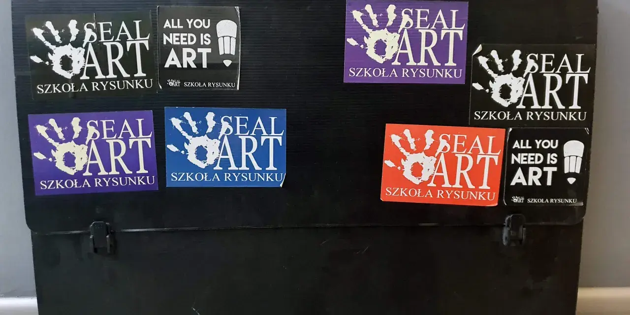 Czarna walizka na prace plastyczne ozdobiona naklejkami "SEAL ART SZKOŁA RYSUNKU" i "ALL YOU NEED IS ART".