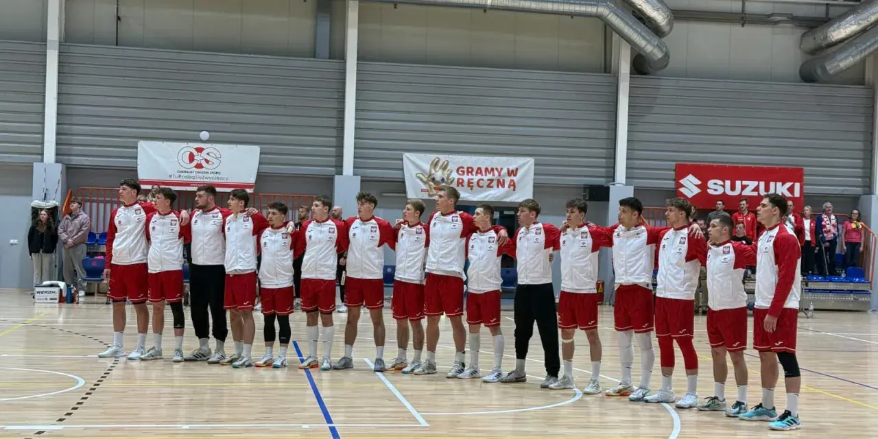 Drużyna w strojach biało-czerwonych, w tym Filip Jankowski, stoi na parkiecie hali sportowej.