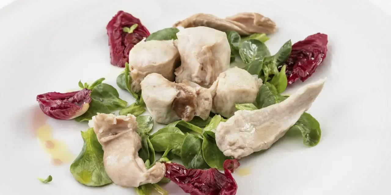Delicato tonno di coniglio servito con insalata fresca e radicchio croccante, condito con olio d'oliva.
