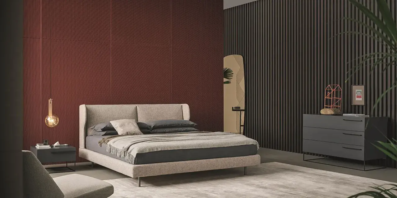 Habitación moderna con pared texturizada en rojo terracota, cama beige y cómoda gris. Inspírate para como pintar una habitacion.