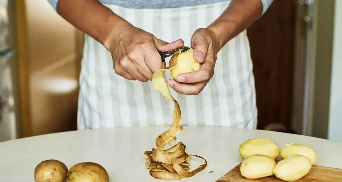 Mani che sbucciano patate per la cottura. Il tempo di cottura patate lesse senza buccia è breve.