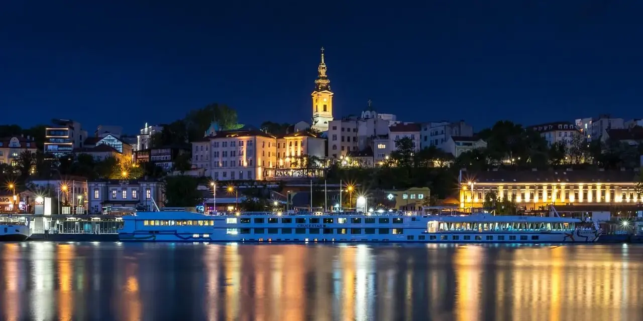 Nocny Belgrad z rzeką i statkiem wycieczkowym. Czy do Serbii potrzebny jest paszport? Sprawdź przed podróżą!
