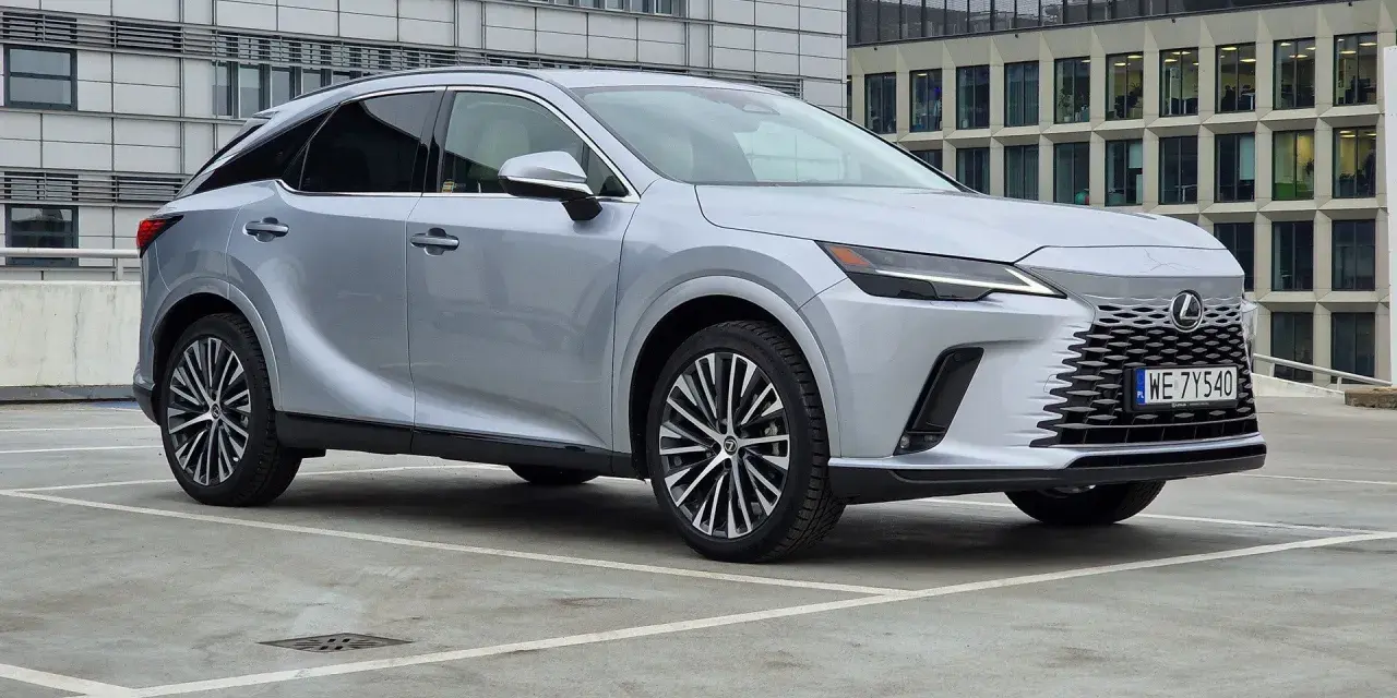 Srebrny Lexus RX 350h zaparkowany przed nowoczesnym budynkiem biurowym.
