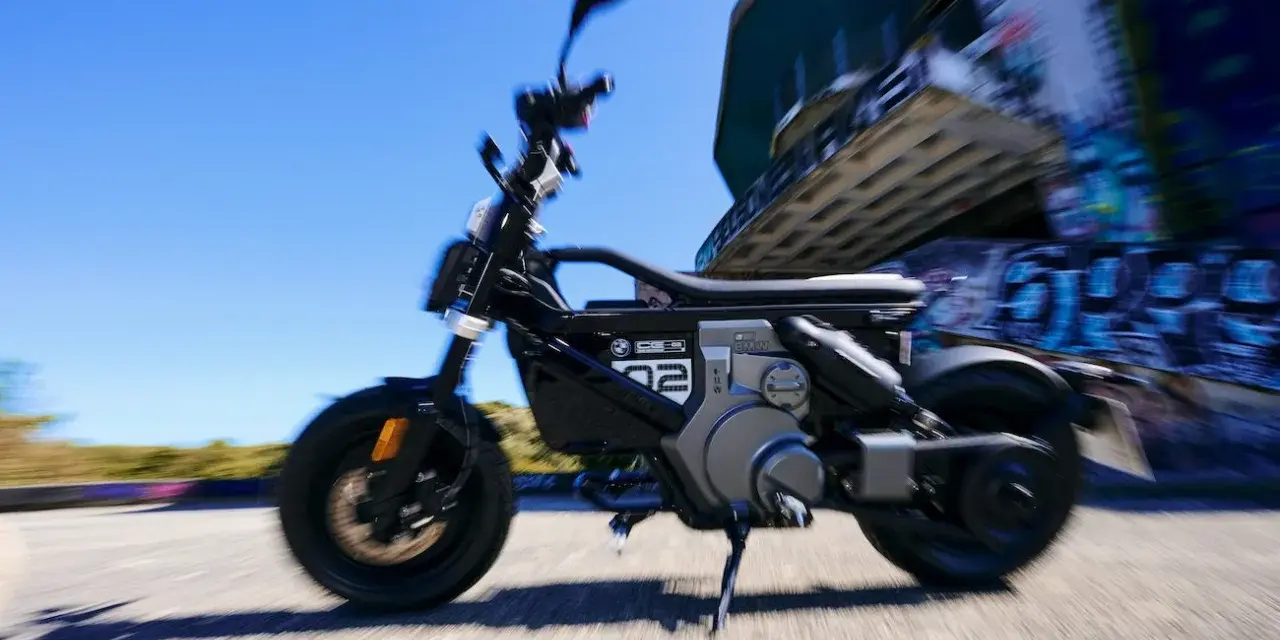 Czarny bmw skuter elektryczny w ruchu, z rozmytym tłem i graffiti.