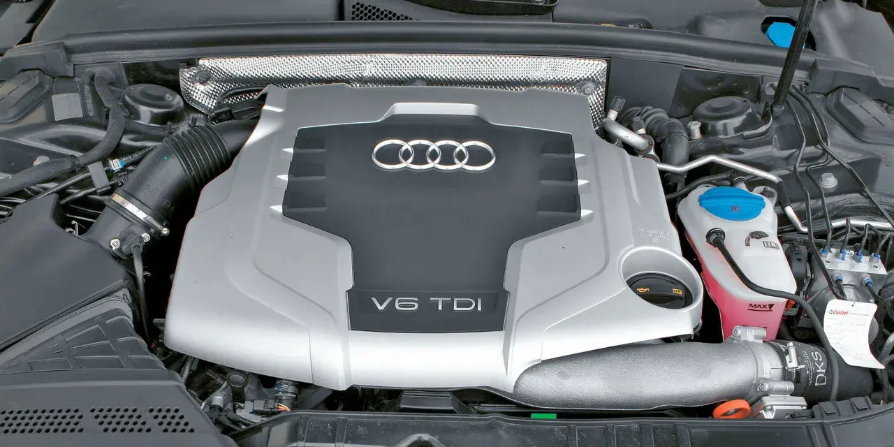 Silnik V6 TDI Audi z widocznym logo i oznaczeniem pojemności. Widać elementy układu dolotowego i płyny eksploatacyjne.