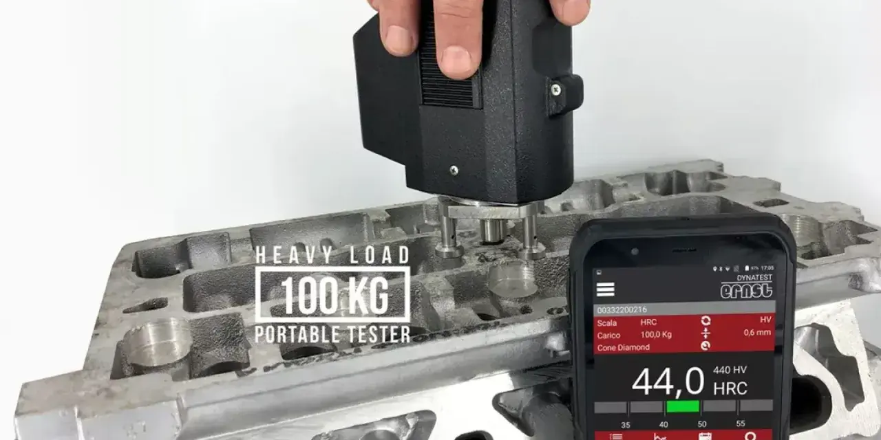 Przenośny tester z obciążeniem 100 kg mierzy twardość materiału, pokazując wyniki na skali twardości na ekranie smartfona.