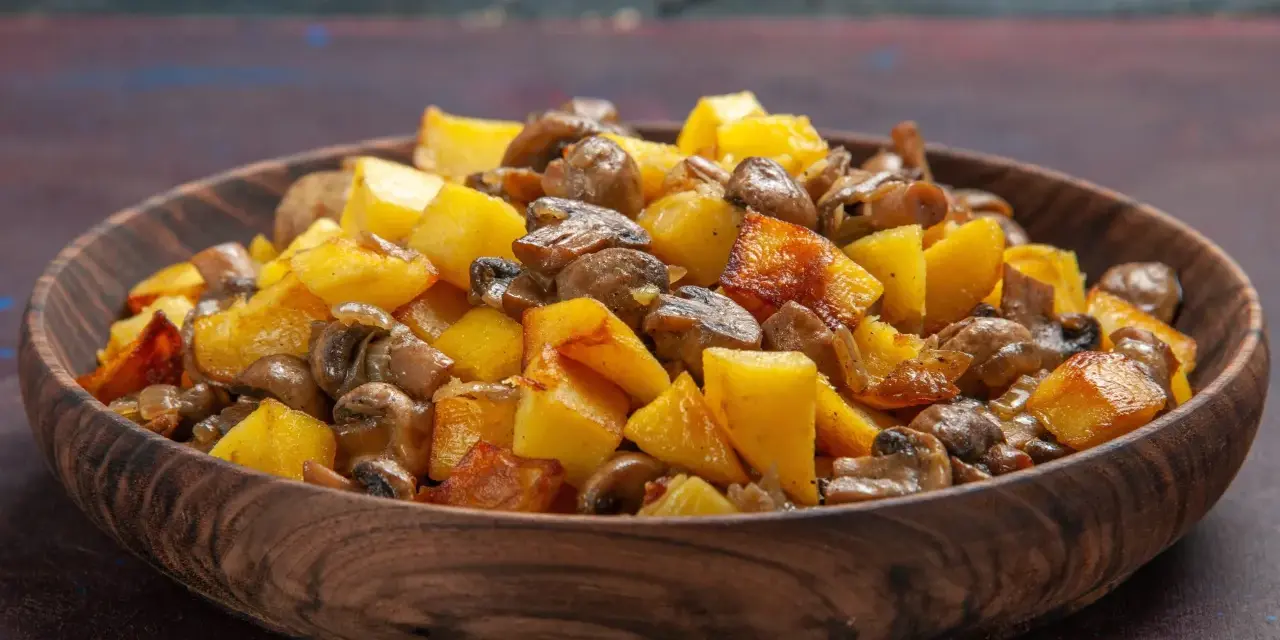 Un delicioso salteado de setas y patatas doradas en un cuenco de madera.
