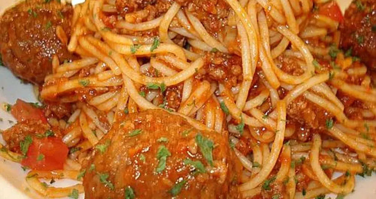 Pyszne spaghetti z pulpetami w sosie pomidorowym, posypane natką pietruszki. Klasyczne danie, które zawsze smakuje wyśmienicie.