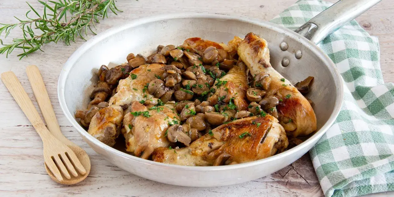 Delizioso pollo con funghi in padella, guarnito con prezzemolo fresco e accompagnato da rosmarino.