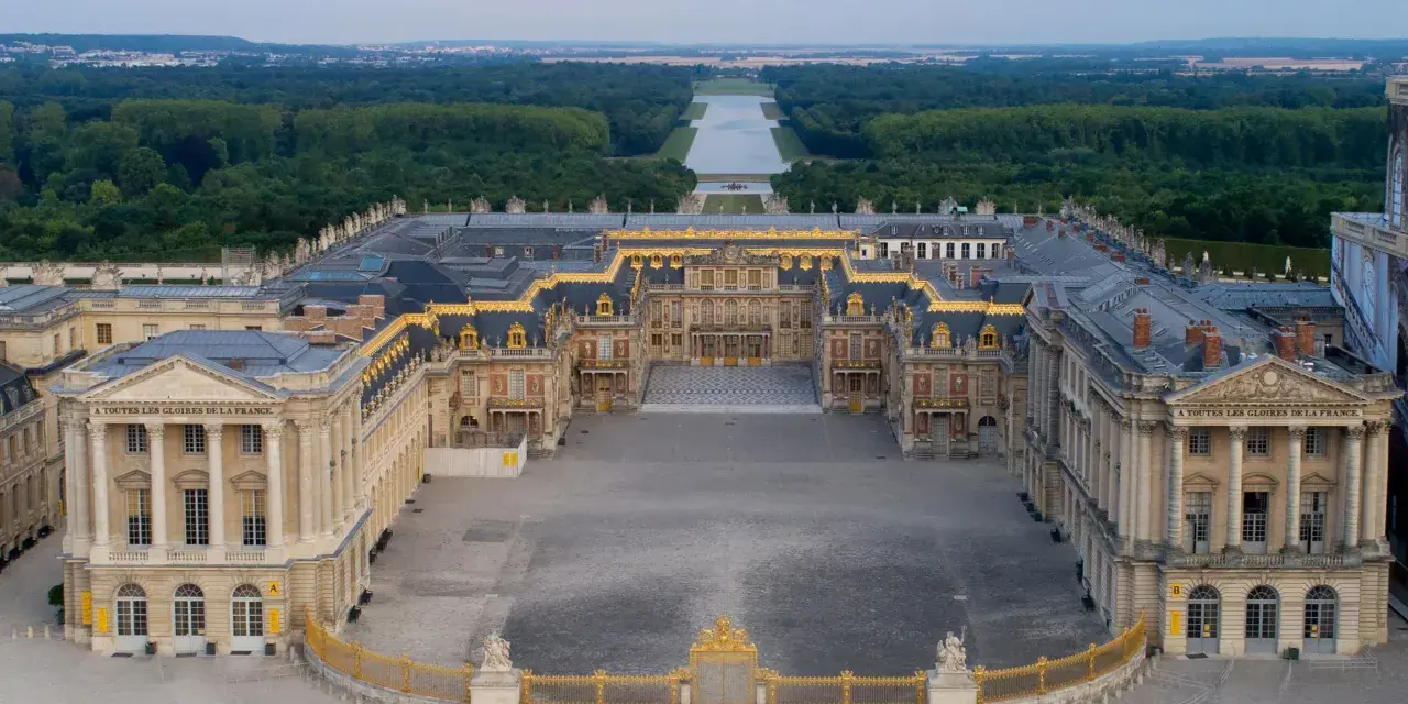 Le château de Versailles, construit par Louis XIV, s'étend majestueusement avec ses cours pavées et ses jardins.