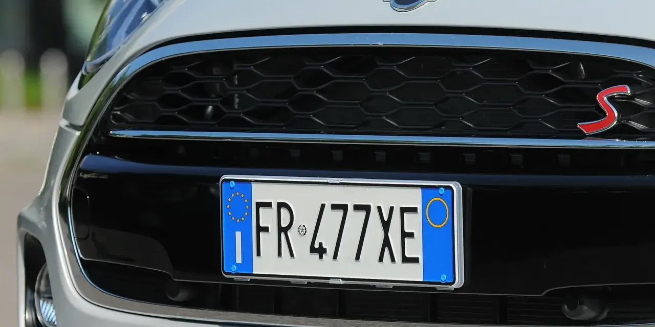 Targa di immatricolazione auto estera su una Mini Cooper S bianca.