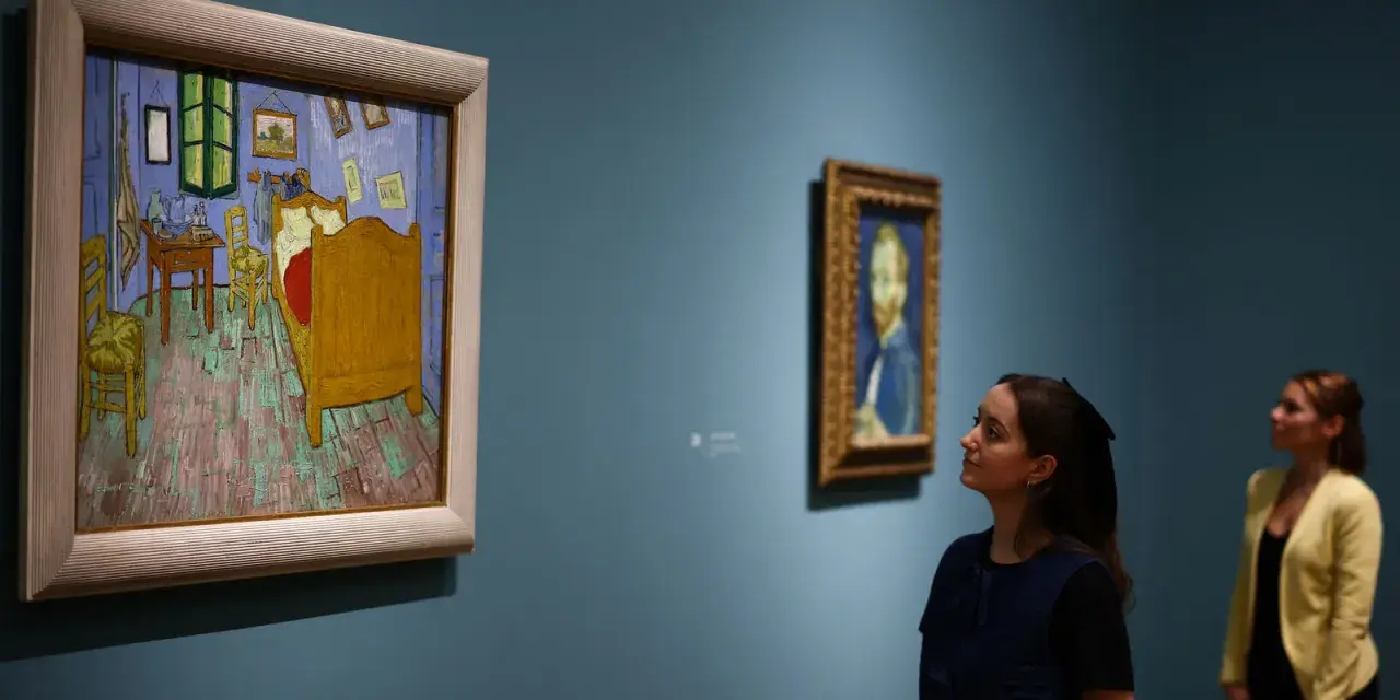 Deux femmes contemplent des tableaux. À gauche, la chambre de Van Gogh, une œuvre iconique dont le prix tableau peinture à l'huile fascine.