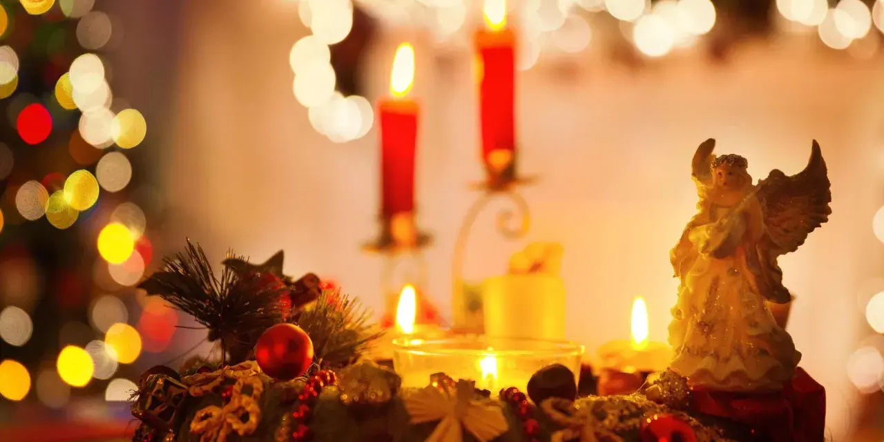Ein Adventskranz mit Kerzen und einem Engel, umgeben von Weihnachtsbaumlichtern.