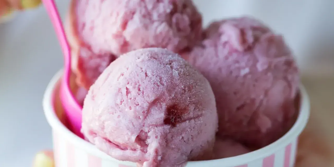 Różowe lody w kubeczku, z różową łyżeczką. Zastanawiasz się, ile kalorii mają lody?