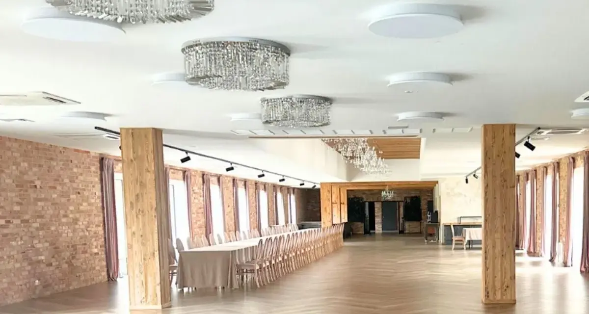 Elegancka sala weselna z kryształowymi żyrandolami i długimi stołami. Zastanawiasz się, ile kosztuje wesele na 120 osób w takim miejscu?