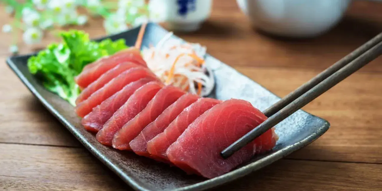 Vackert upplagd tonfisk sashimi på en tallrik, redo att avnjutas med en god vin.
