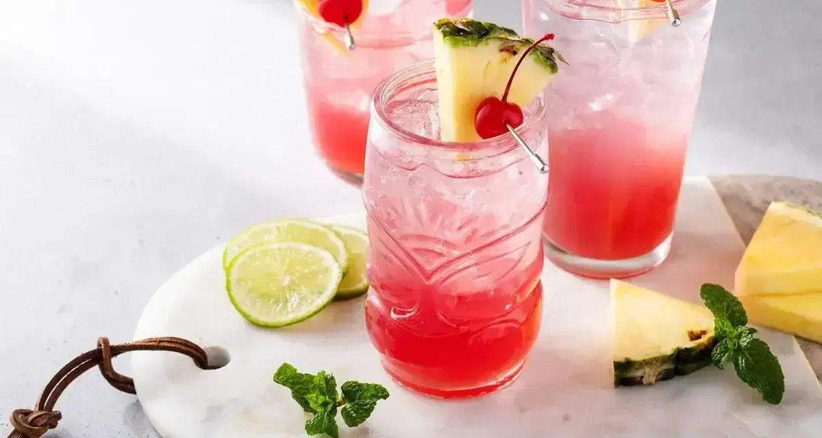 Orzeźwiający drink z ginem, ozdobiony ananasem i wiśnią, z dodatkiem limonki i mięty. Idealny na letnie popołudnie.