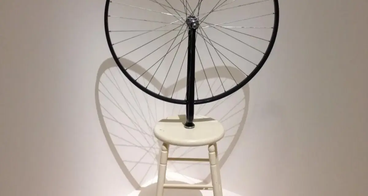Roue de vélo fixée sur un tabouret, une œuvre emblématique de Marcel Duchamp, projetant une ombre fascinante.