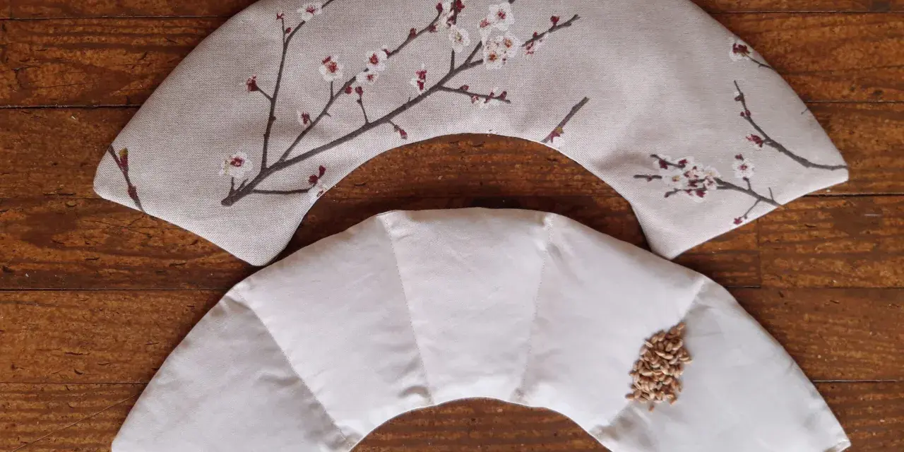 Tuto bouillotte sèche cervicale : deux coussins en tissu, l'un décoré de fleurs de cerisier, l'autre prêt à être rempli de grains.