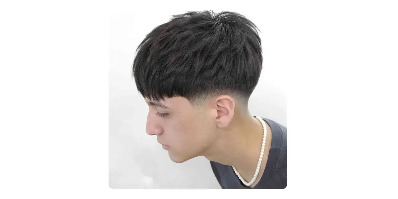 Joven con corte de pelo moderno, con un degradado hombre en los laterales y la parte superior texturizada.