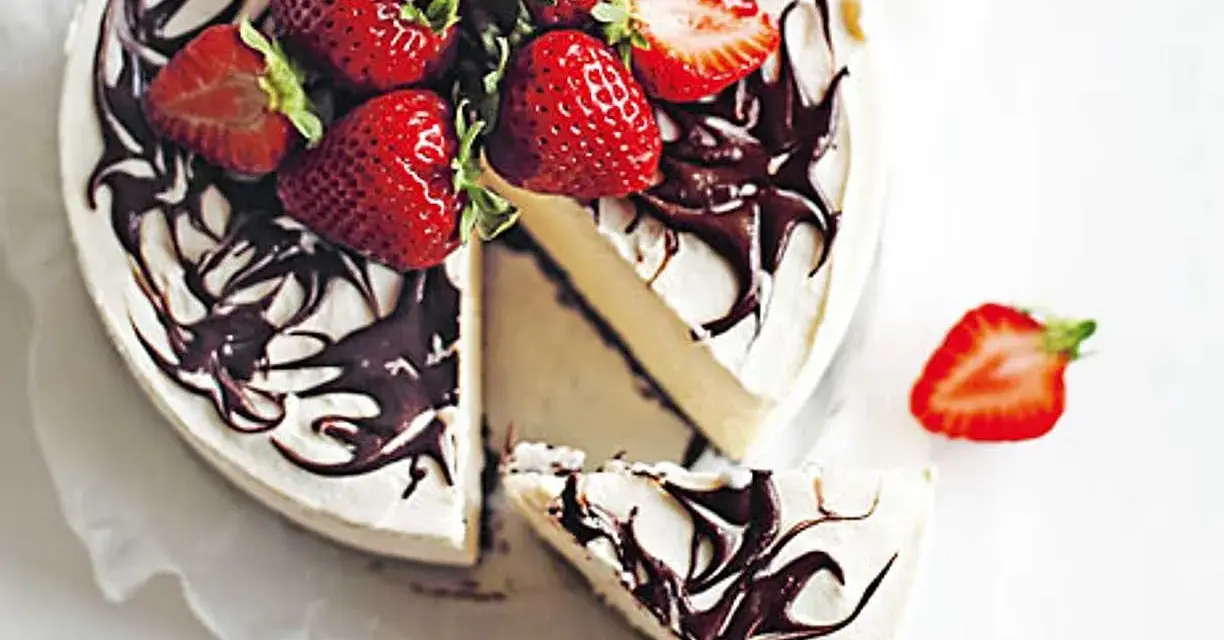 En krämig no bake cheesecake med chokladdrizzle och färska jordgubbar. En bit är uppskuren.