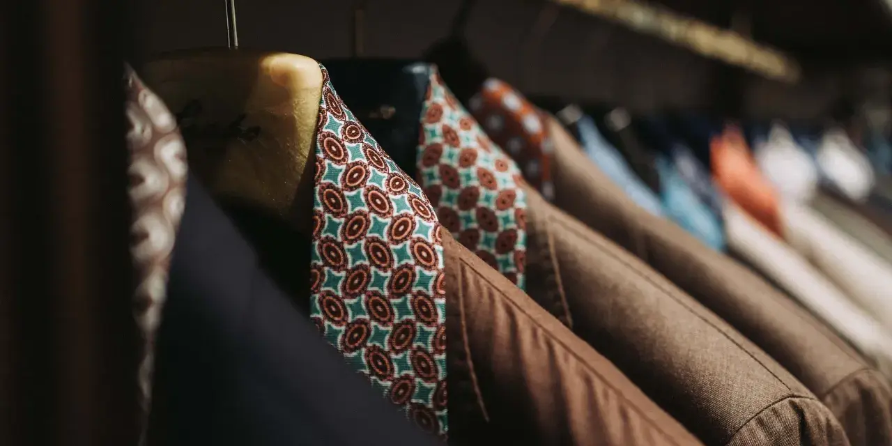 Un guardaroba elegante con giacche marroni e camicie dal tessuto dalle tinte diverse e vivaci, con fantasie geometriche.