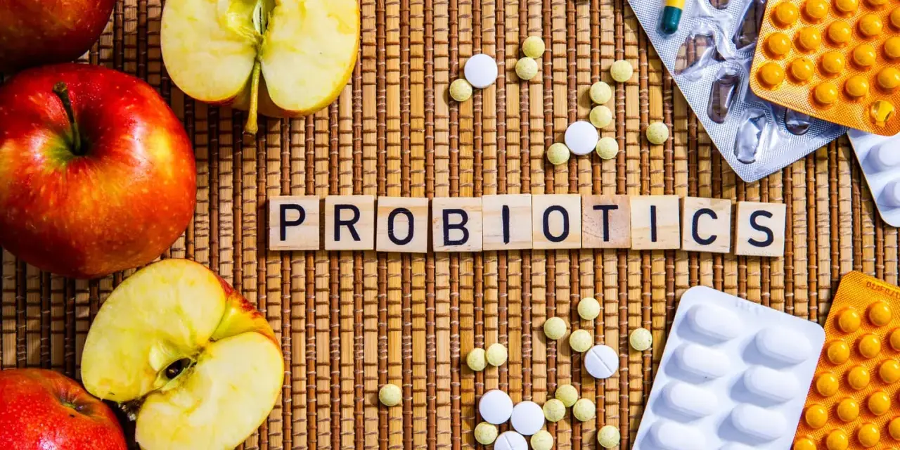 Äpfel und Pillen umgeben das Wort "PROBIOTICS". Eine natürliche Methode, probiotika gegen akne zu finden.