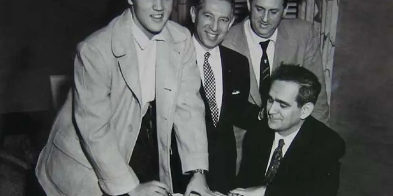 Elvis Presley unterschreibt Dokumente, ein wichtiger Schritt für seinen späteren Elvis Presley net worth.