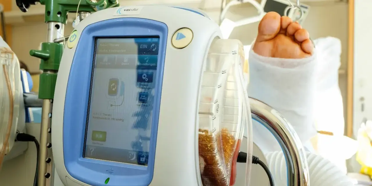 V.A.C.® Therapy Gerät mit gefülltem Behälter und einem Fuß im Verband. Die vac pumpe unterstützt die Wundheilung.