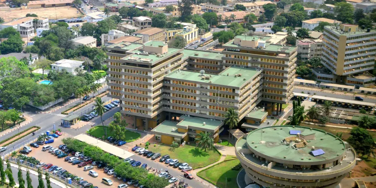 Widok z lotu ptaka na nowoczesne budynki w Lome, Togo, z zielonymi dachami i parkingami pełnymi samochodów.