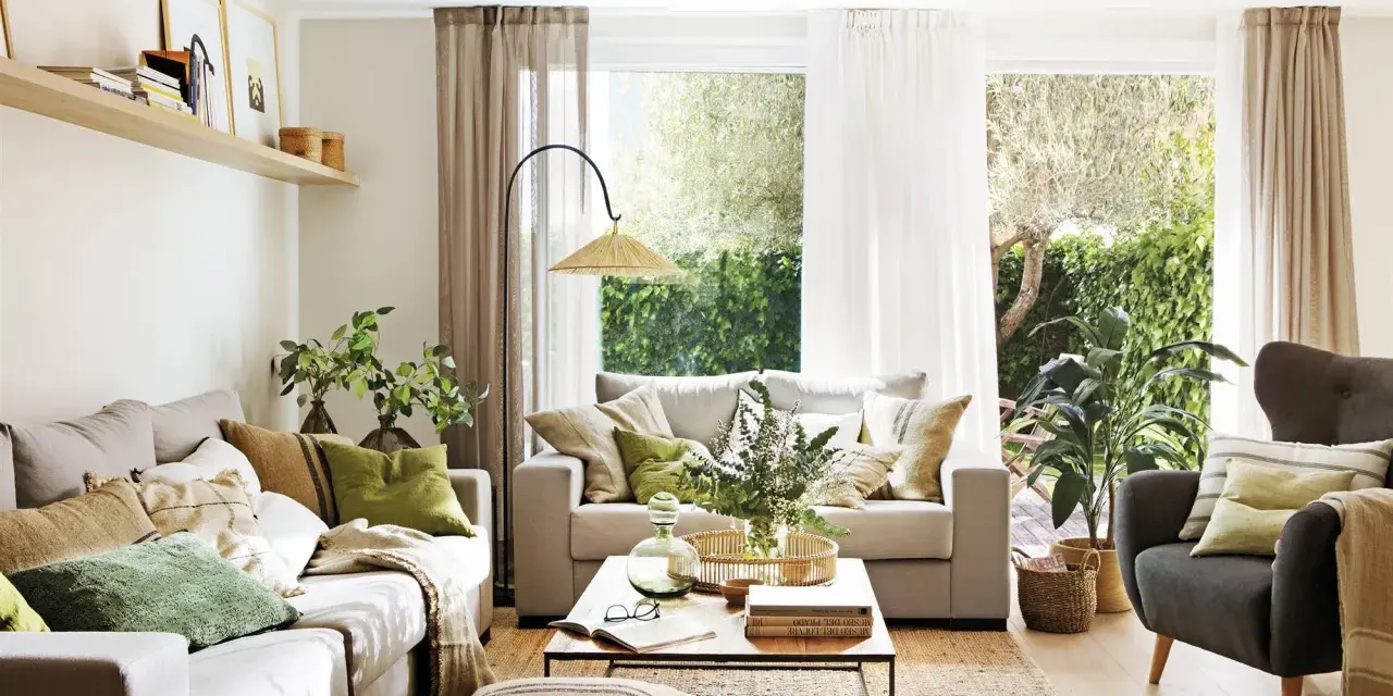 Salón con sofás, sillón, mesa de centro y alfombra de yute. La decoracion aesthetic se realza con cojines en tonos tierra y verdes, plantas y luz natural.