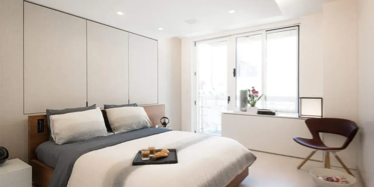 Camera da letto moderna con letto king-size, pannelli imbottiti e soffitto con faretti e strisce led controsoffitto che creano un'atmosfera rilassante.