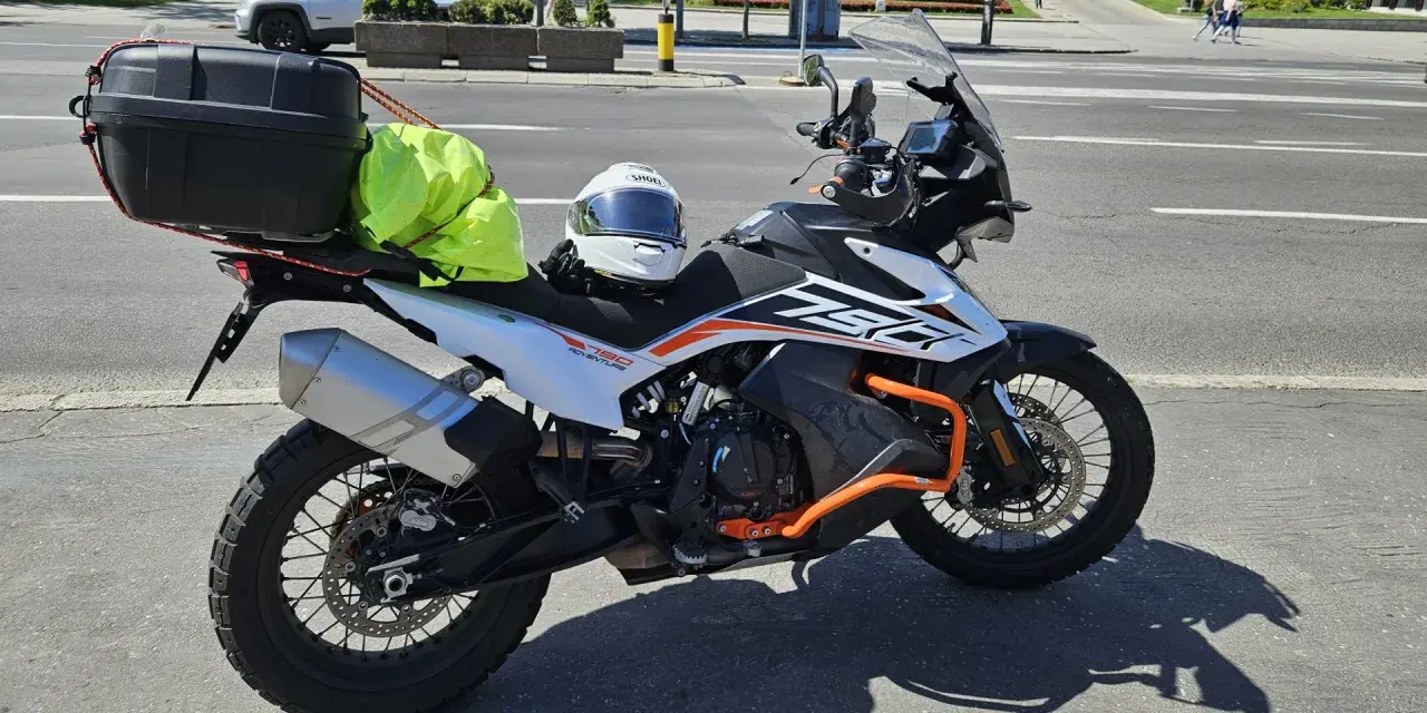 Motocykl KTM 790 Adventure gotowy na przygodę po NC500 Szkocja. Kask i jaskrawożółty pokrowiec na bagaż czekają na start.