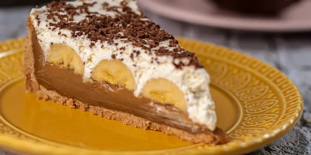 Kawałek banoffee pie z bananami, kremem i czekoladą na żółtym talerzu. Nie tarta cytrynowa, ale pyszny deser!