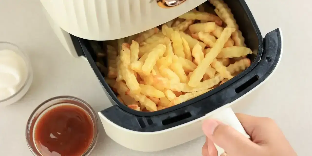 Air fryer co to? To urządzenie, które przygotuje chrupiące frytki bez nadmiaru tłuszczu. Obok sosy i majonez.