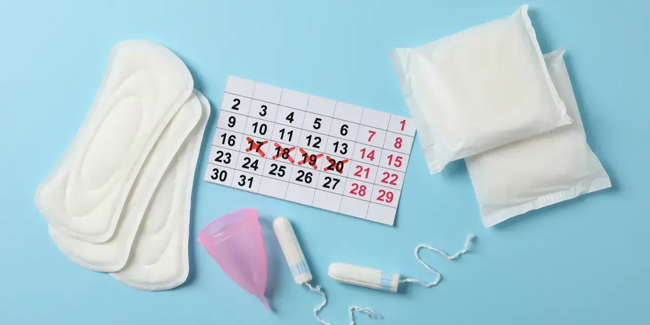 Kalender mit markierten Tagen, Binden, Tampons und Menstruationstasse. Fragen zu Zwischenblutung trotz Pille schwanger?