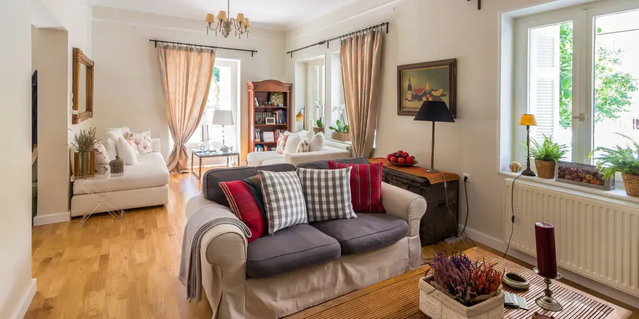 Przytulny salon w stylu angielskim z wygodnymi sofami, drewnianą podłogą i stylowymi dodatkami.