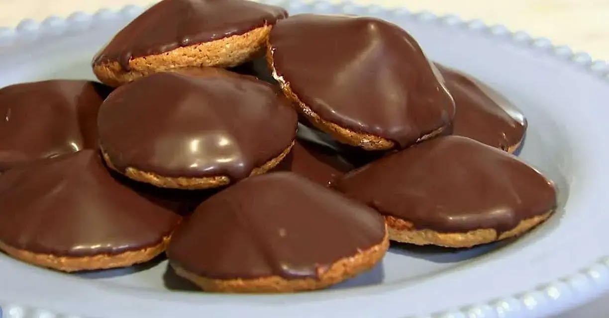 En hög med chokladöverdragna biskvier på en ljusblå tallrik. Perfekt för ett enkelt biskvier recept.