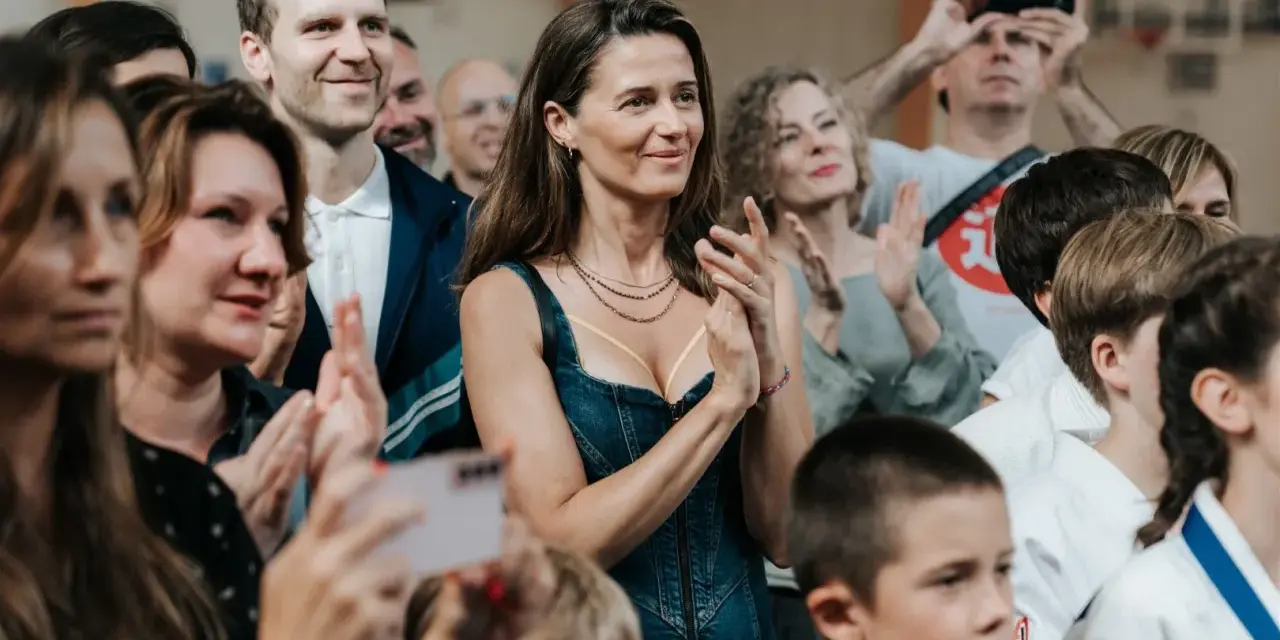 Agnieszka Grochowska z uśmiechem klaszcze, otoczona ludźmi na widowni.