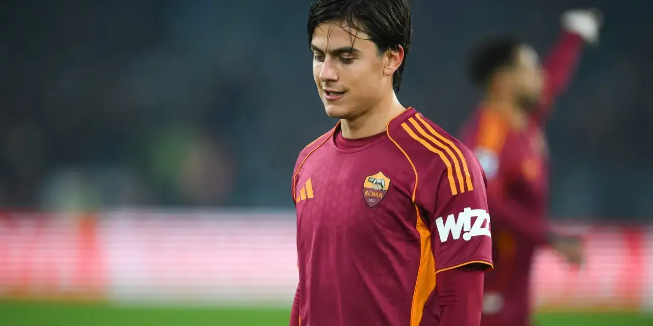 Piłkarz AS Roma w bordowej koszulce z pomarańczowymi pasami, gotowy do gry przeciwko Atalancie.