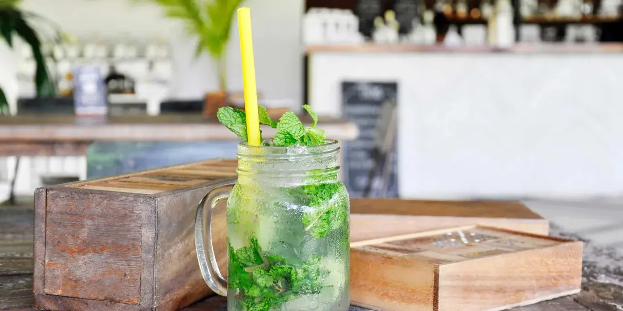 Erfrischender Mojito mit Minze und Eis in einem Glas. So trinkt man Rum an einem heißen Tag.
