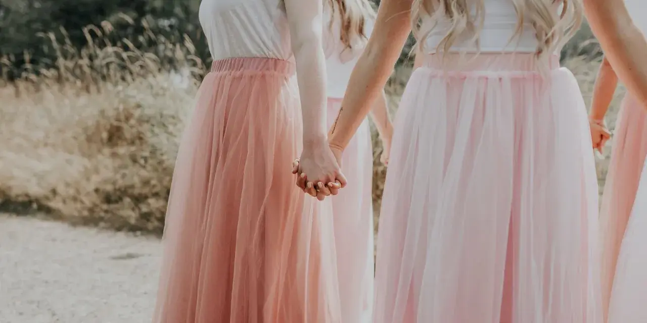 Dziewczyny w tiulowych, pudrowych sukienkach trzymają się za ręce. Ich styl to kwintesencja "soft girl".